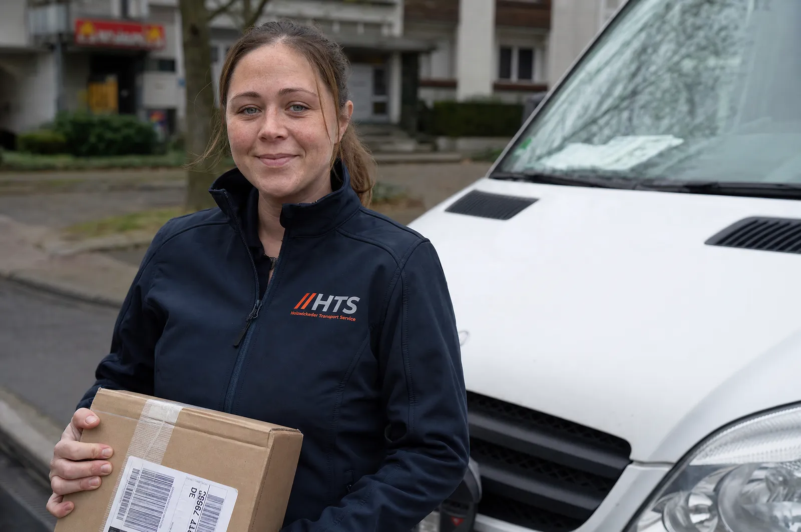 HTS-Kurierfahrerin mit Paket am Sprinter